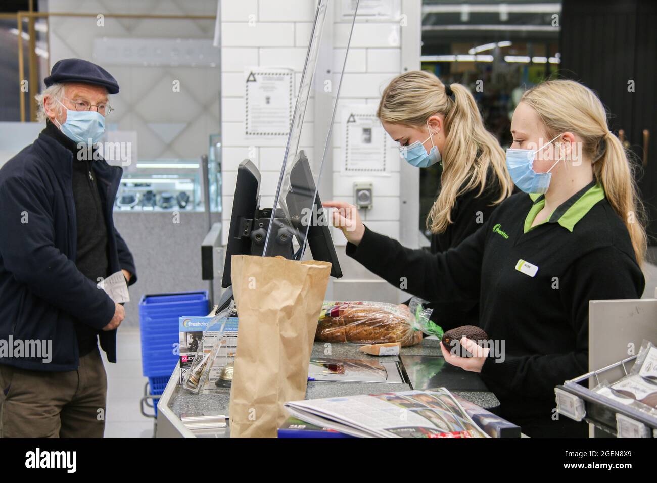 Fresh choice supermarket Staff members wearing face masks as a preventive measure against the spread of coronavirus serve a customer during the lockdown.New Zealand's outbreak of the Delta variant has so far seen 28 confirmed cases in Auckland, and three in Wellington. Prime Minister Jacinda Ardern yesterday placed areas outside Auckland and Coromandel into a further lockdown until 11.59 pm on Tuesday. Deputy Prime Minister Grant Robertson said this morning, “things will get worse before they get better”, and that “there will be more cases”. He said he hadn't yet had the update on today's numb Stock Photo