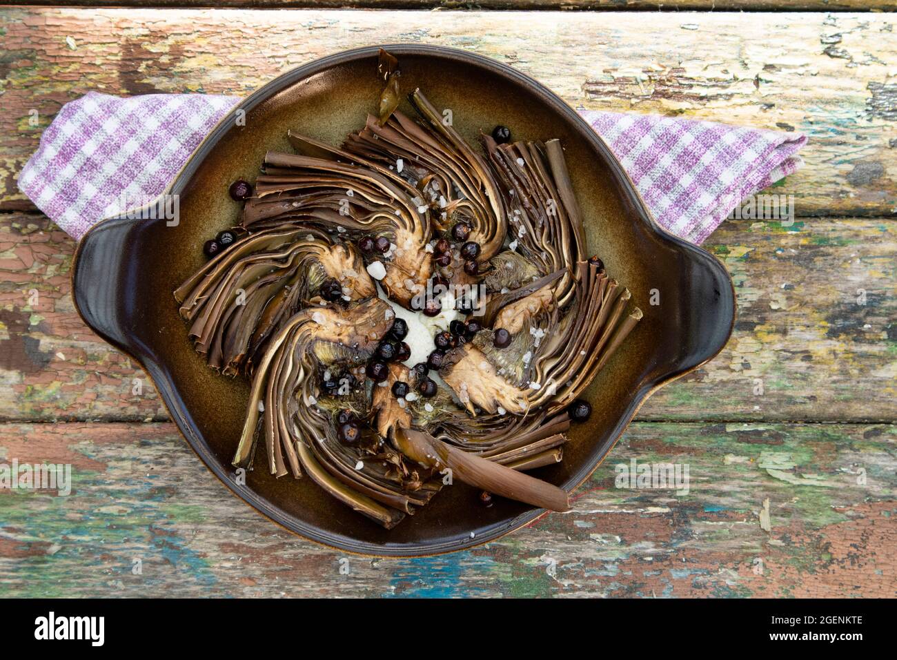 Presentation of a dish of artichokes baked in the oven with a juniper