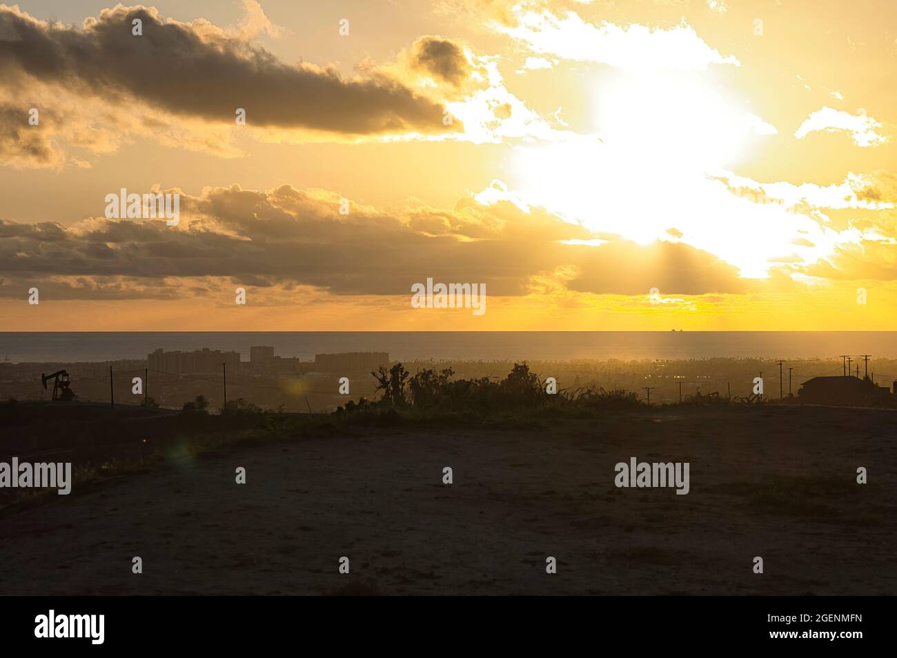 sunlight streaming through clouds at sunset over grassy beach in late afternoon Stock Photo