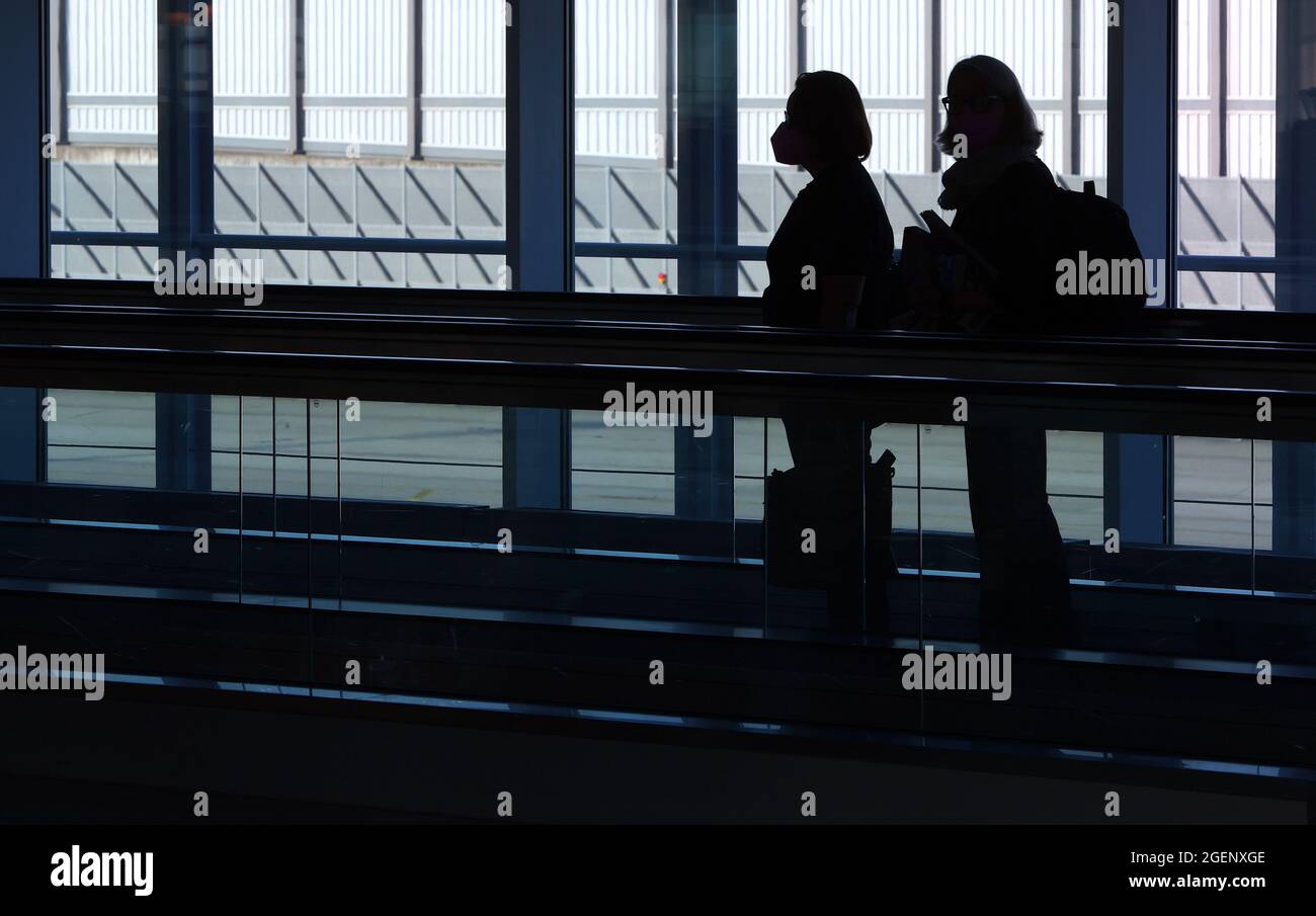 Munich, Germany. 21st Aug, 2021. Travellers stand on a conveyor belt at Franz-Josef-Strauß Airport. Credit: Karl-Josef Hildenbrand/dpa/Alamy Live News Stock Photo