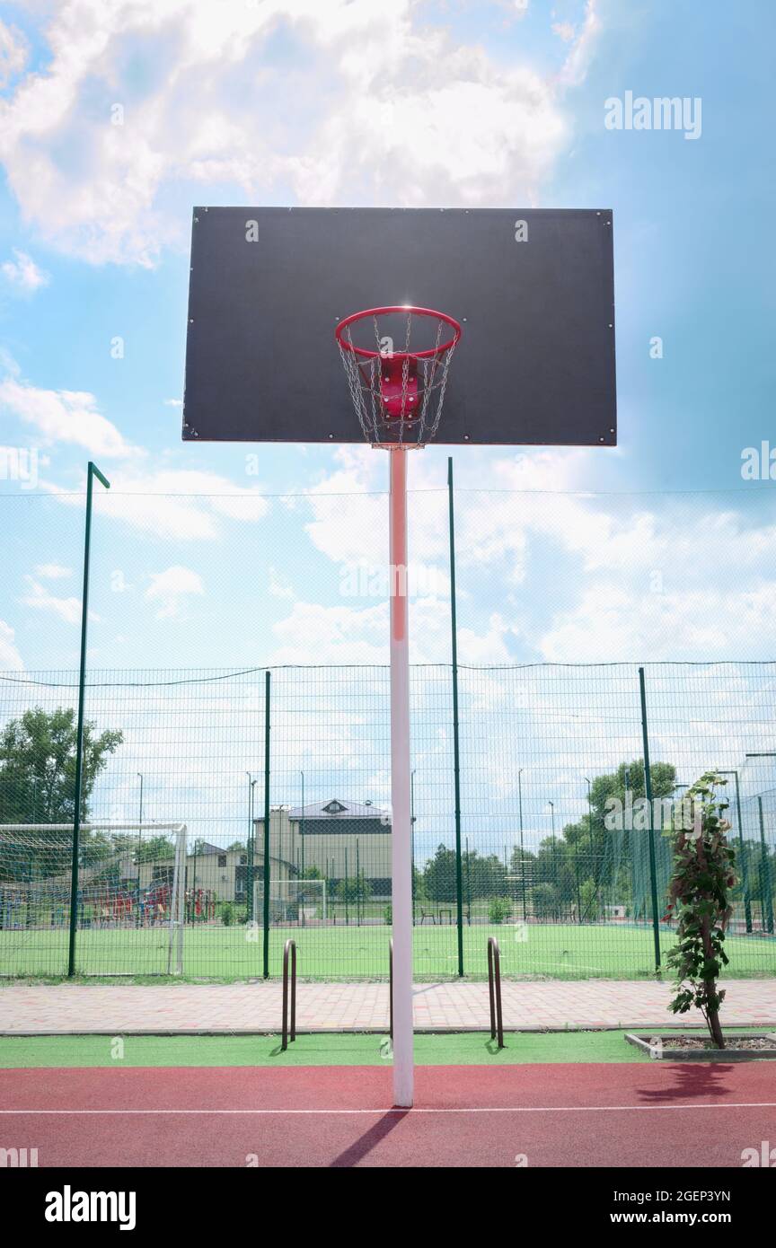 Basketball backboard with a basket made of iron chains on a sunny day. Vertical view. Low angle view Stock Photo