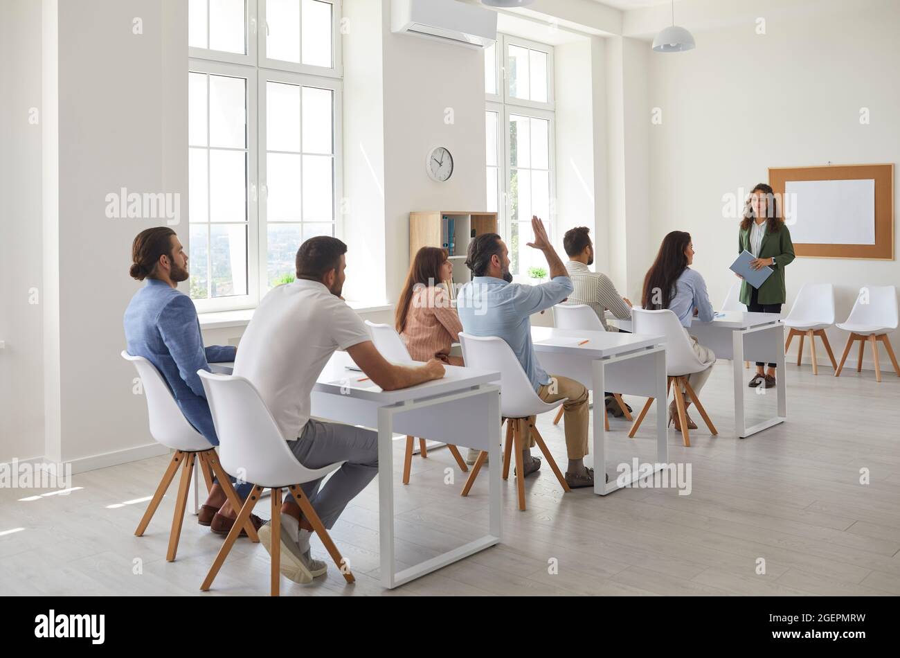 Group of workers sitting at tables in the classroom in a lesson with a professional business coach Stock Photo