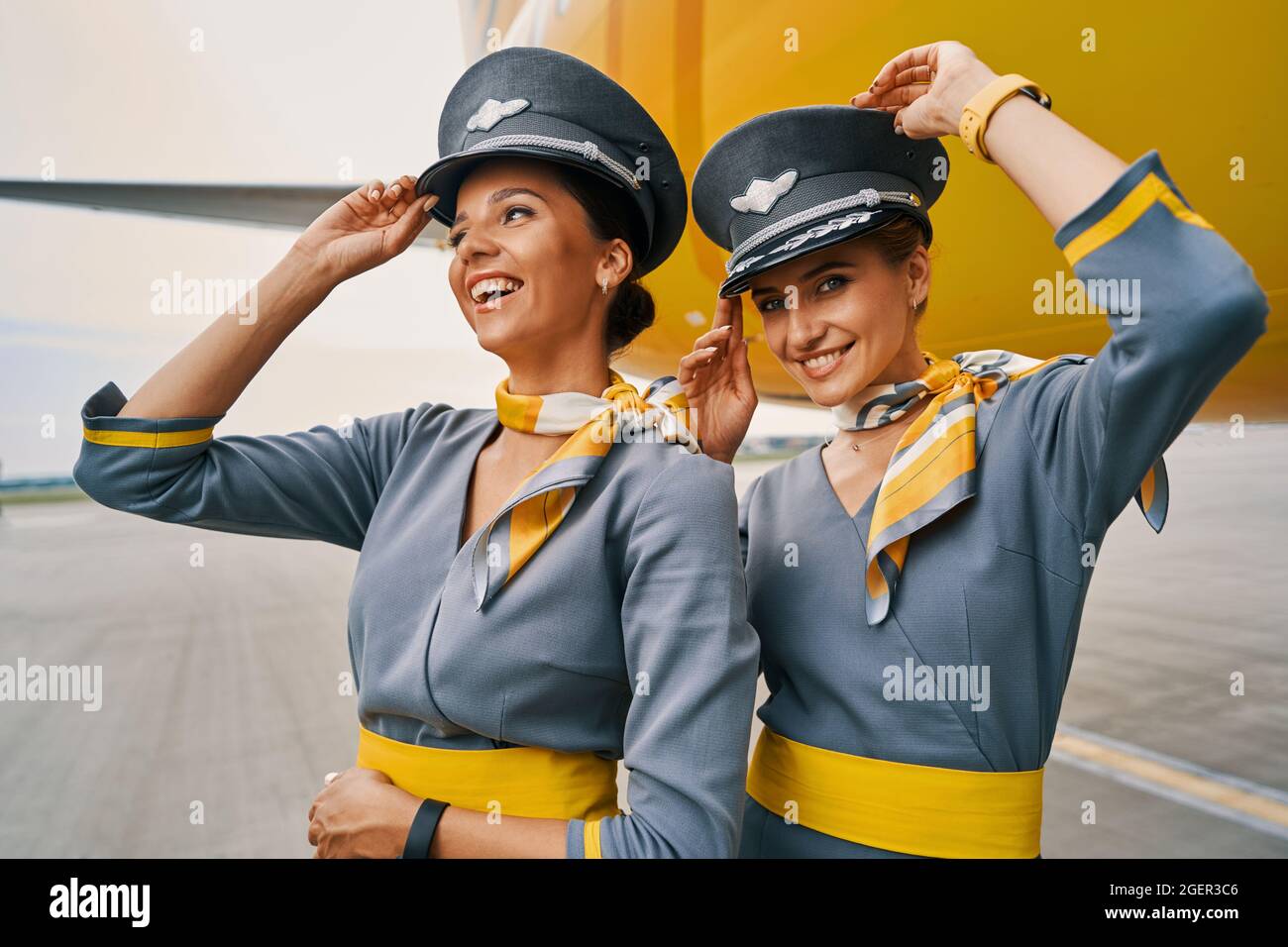 Joyous air hostesses in uniforms by a landed aircraft Stock Photo Alamy