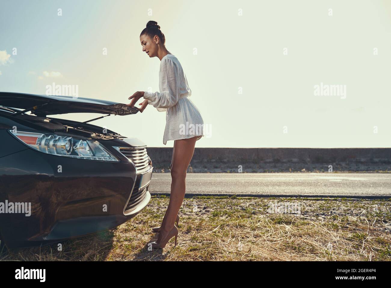 Careful woman is lifting hood of car Stock Photo Alamy