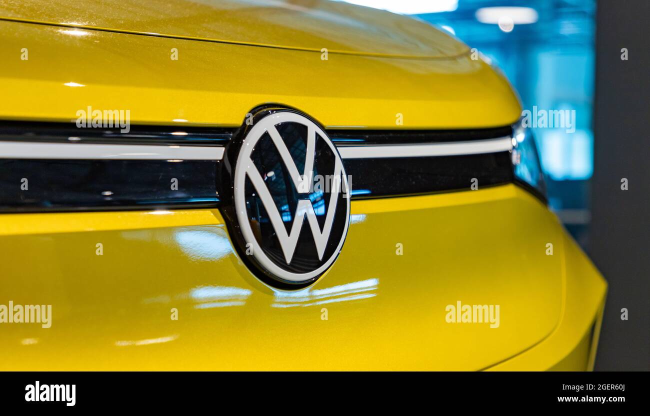 A picture of a Volkswagen logo on the front of a bright yellow car. Stock Photo