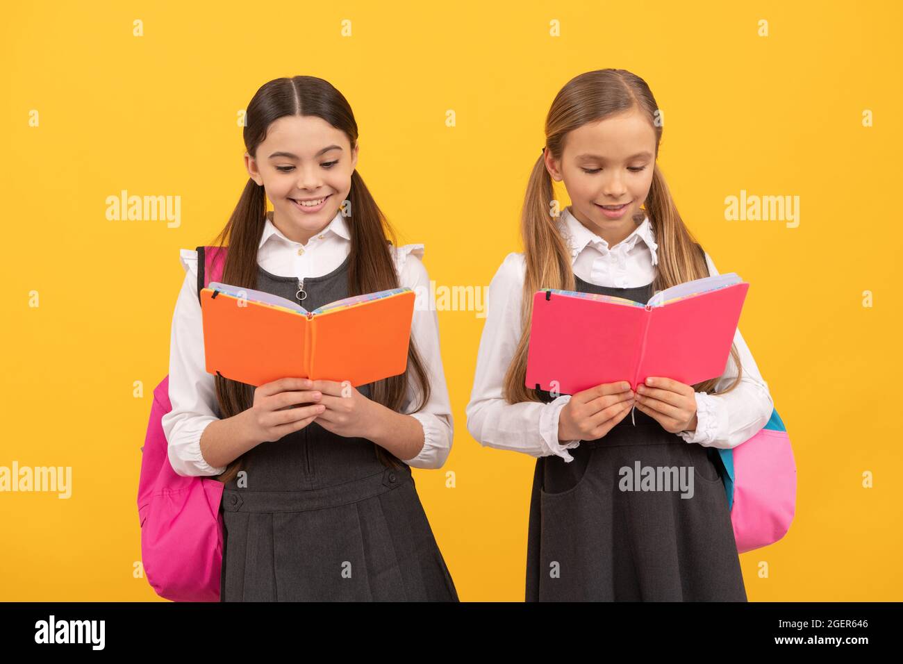 Little children in school uniforms read library books yellow background, reading Stock Photo