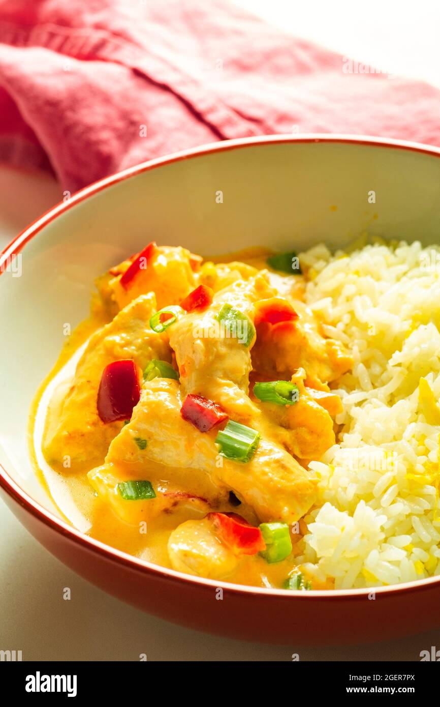 Thai Chicken Curry with Rice in a Red and White Bowl with a Pink Napkin Stock Photo