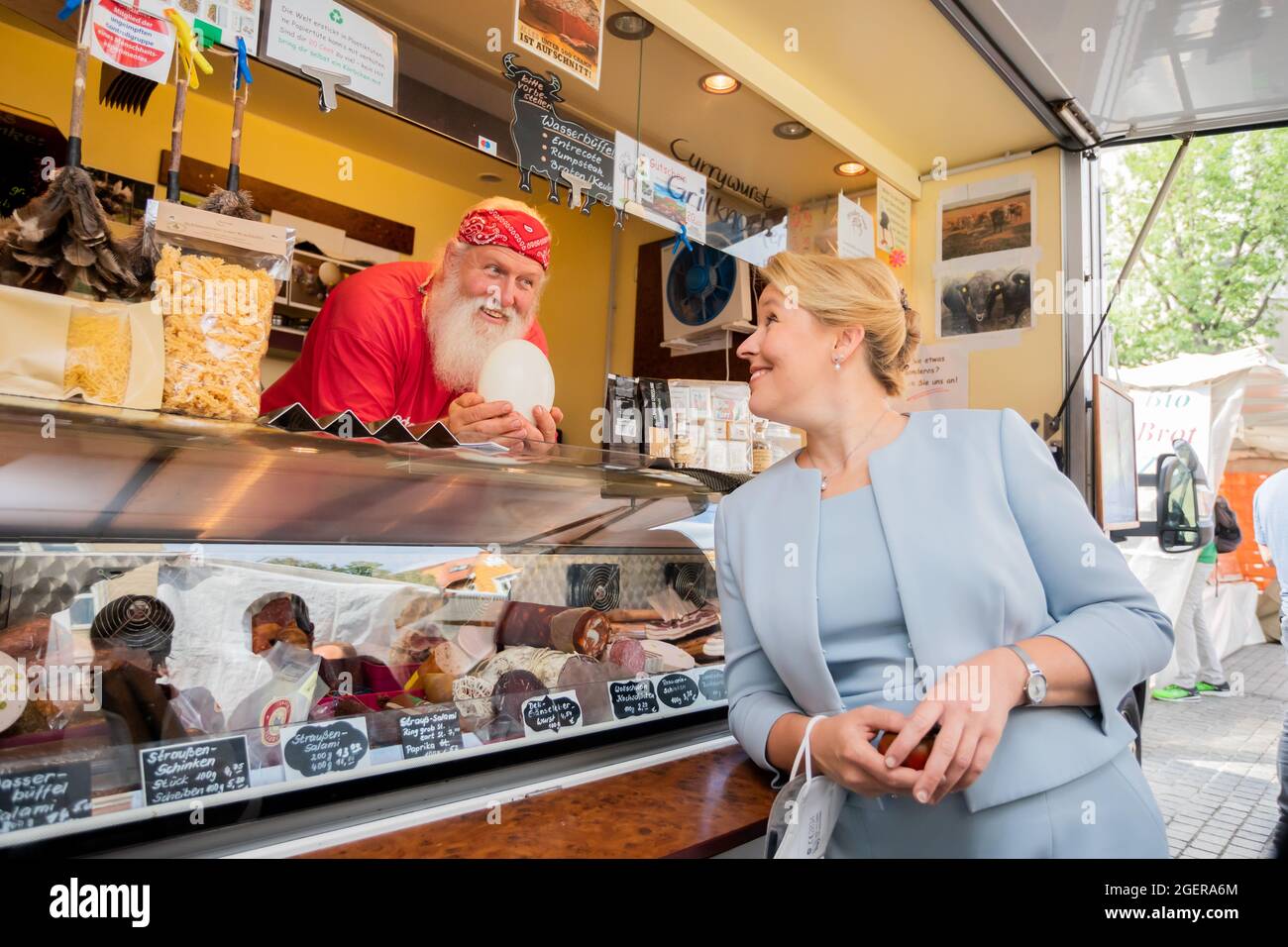 Berlin, Germany. 21st Aug, 2021. Franziska Giffey (SPD), the SPD's top candidate for the Berlin House of Representatives election, has her picture taken with Michael Schütze, a trader of exotic meat products, holding an ostrich egg, during a campaign visit to the Breslauer Platz market in Berlin-Friedenau. Credit: Christoph Soeder/dpa/Alamy Live News Stock Photo