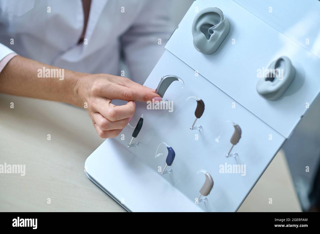 Womans hand touching hearing aid at stand Stock Photo