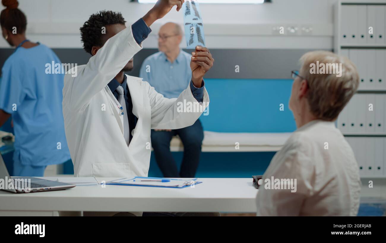 Nurse giving x ray scan to doctor sitting at desk and explaining ...