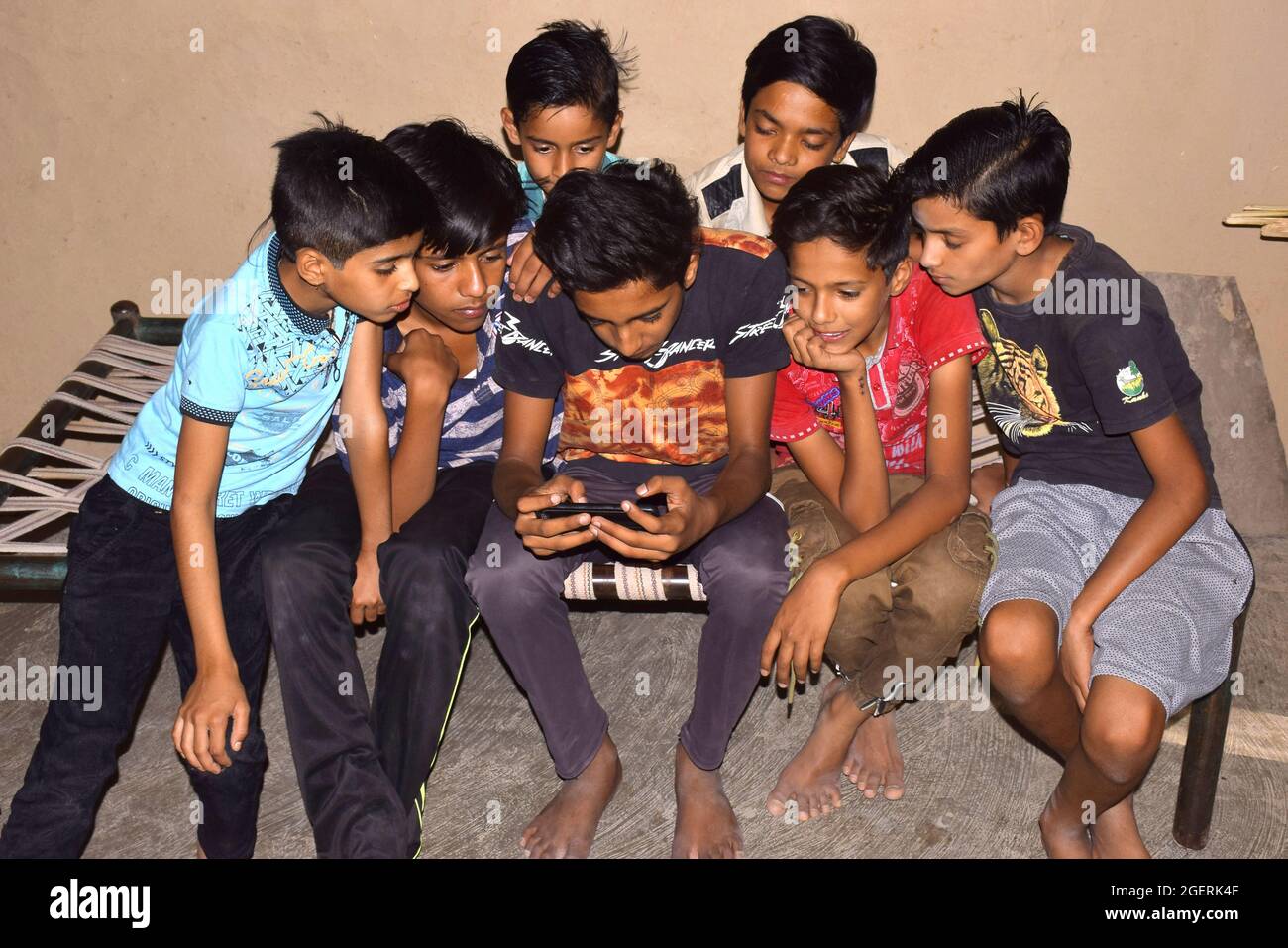30-05-2020,Dewas. M.P. India. rural children sitting on the bed and playing games on mobile phones Stock Photo