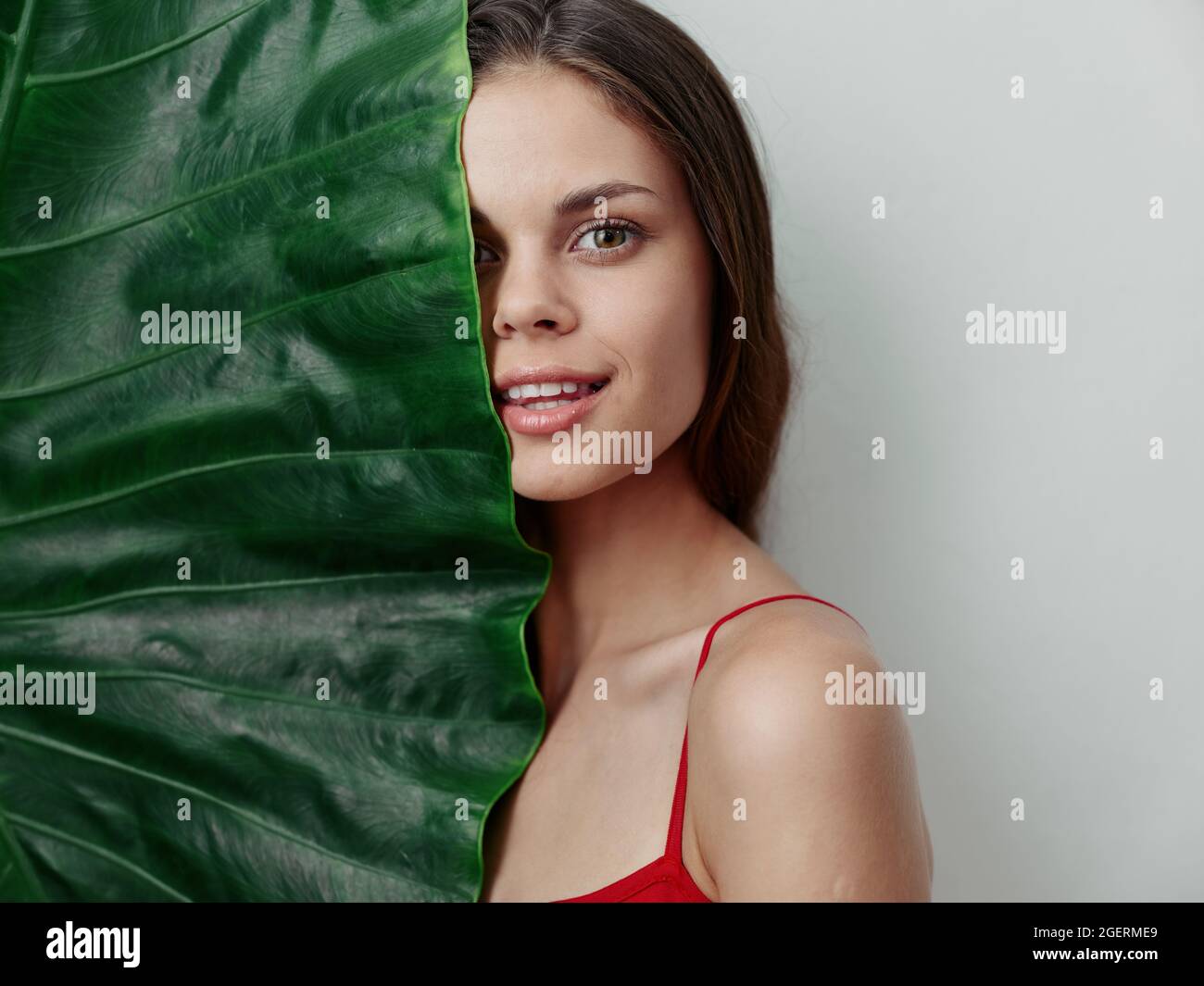 woman covers half of her face with green leaf red swimsuit Stock Photo ...