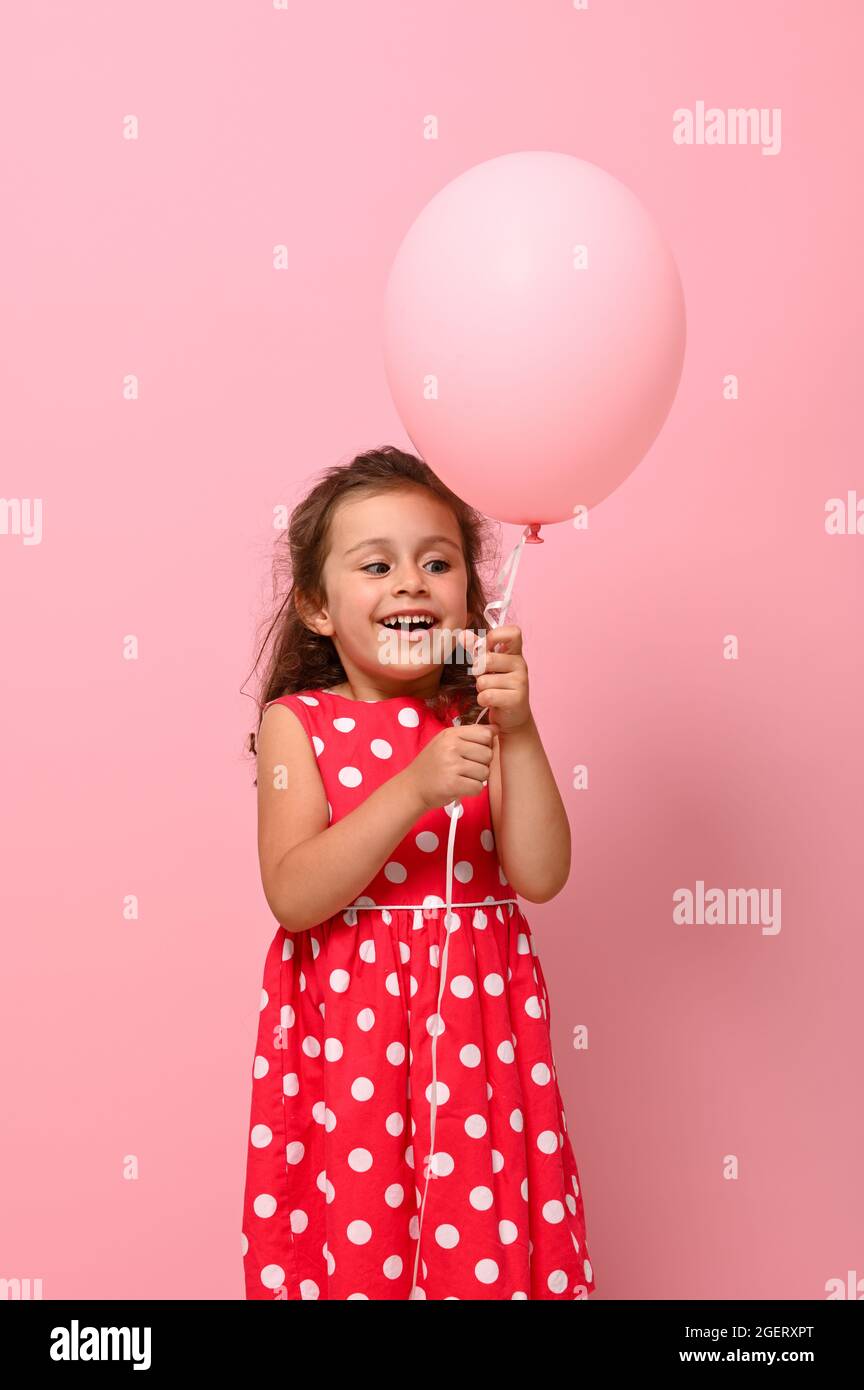 a cute little girls with balloons in the form of a heart in hands on many  colorful heart balloons and big cake background. smiles,funny Valentine s  Day birthday party. | Stock image |