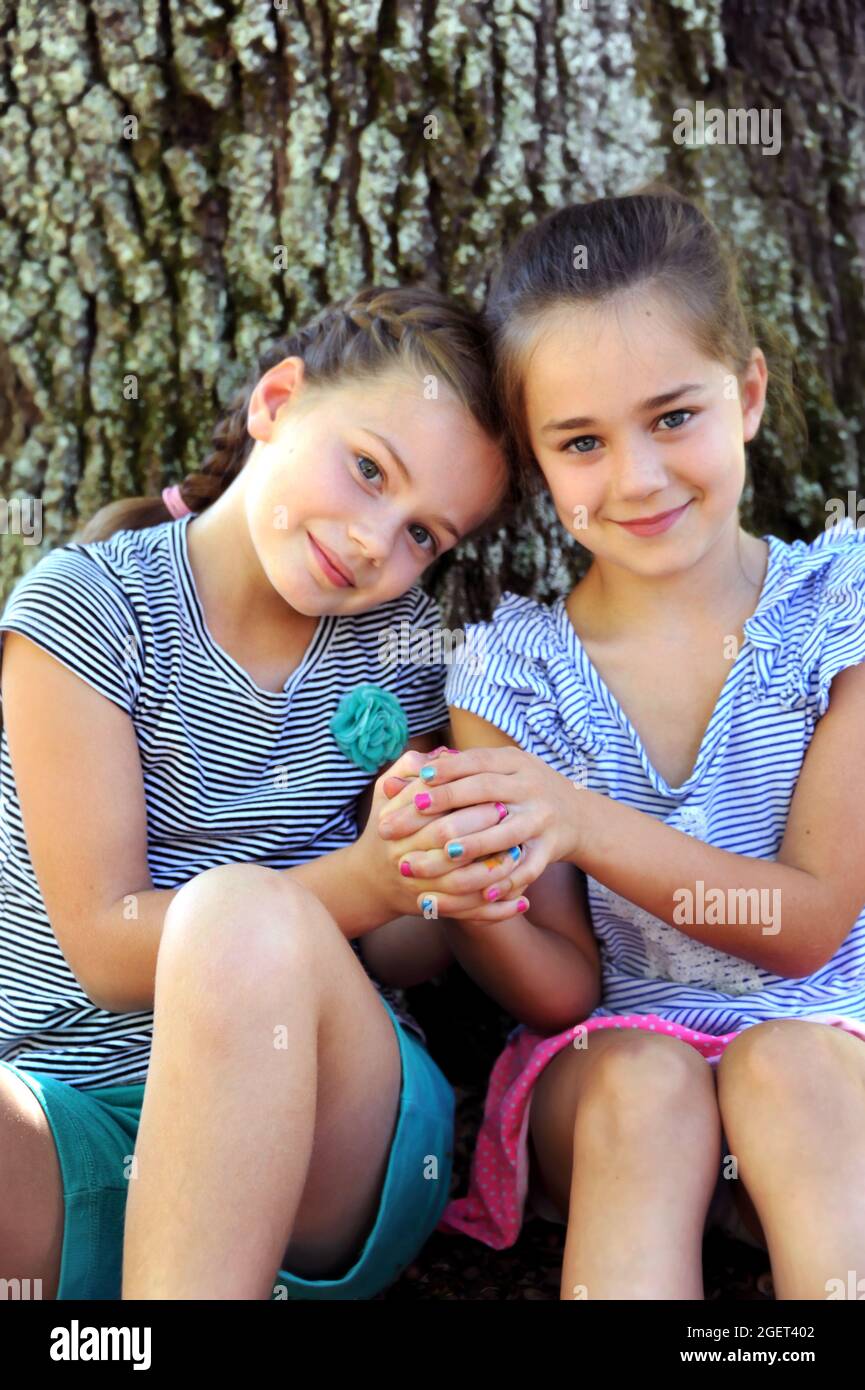 Sisters sit with clasped hands.  Their finger nails show different colors signifying and different personalities.  With hands clasped, they bind toget Stock Photo