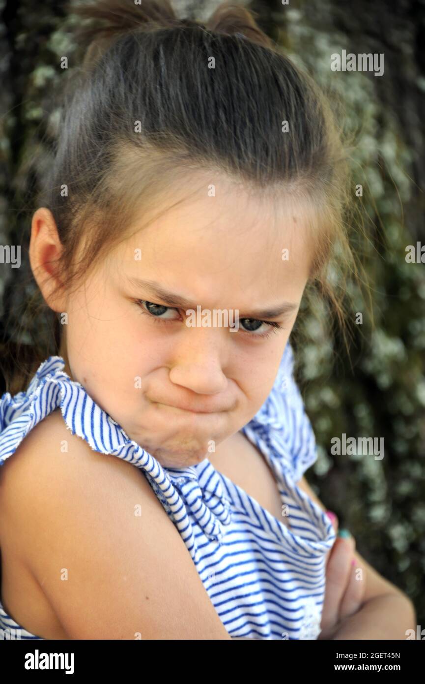 Closeup of this angry little girl, shows puckered brows, eyes shooting daggers, compressed mouth and angry folded arms. Stock Photo