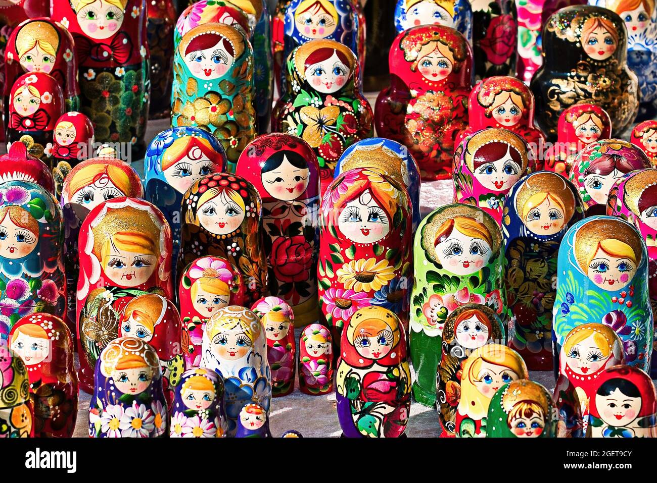 Brightly painted population of wooden Matryoshka or Babuska stacking dolls. Varying sizes. Females faces with red lipstick and rosy cheeks. Girls in t Stock Photo