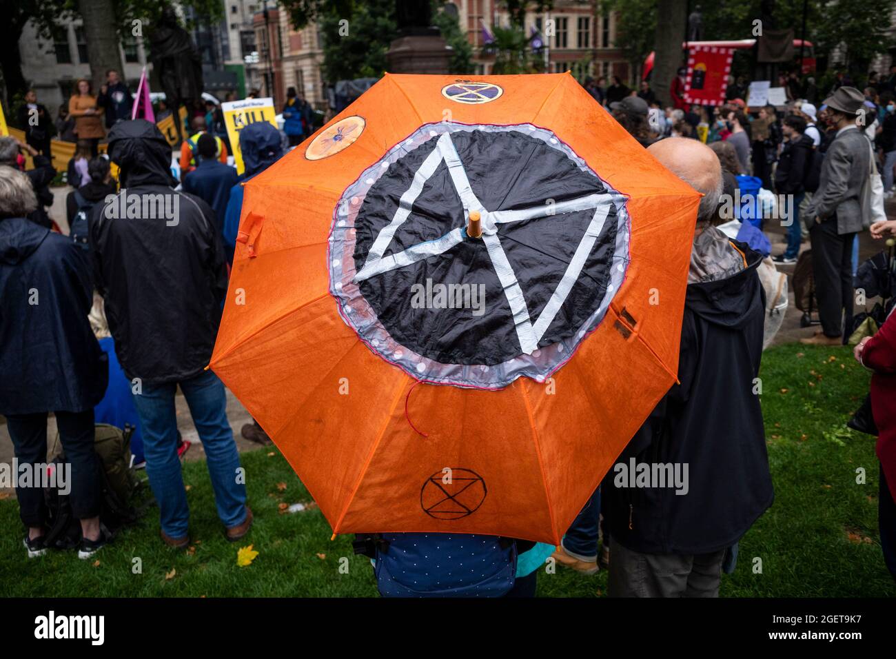 London, UK.  21 August 2021. A person with an umbrella bearing the Extinction Rebellion logo at a Kill the Bill protest in Parliament Square where people are campaigning against the Police, Crime, Sentencing and Courts Bill Government Bill.  Members of climate activists Extinction Rebellion (XR) are also present ahead of reported climate protests targeting the City of London next week.  Credit: Stephen Chung / Alamy Live News Stock Photo