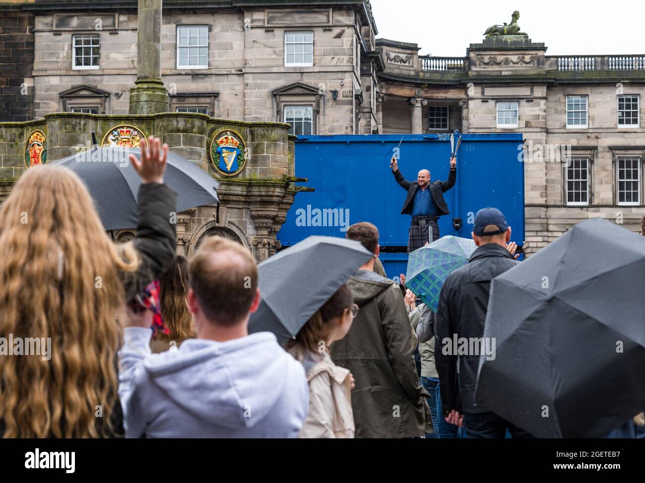 Royal Mile, Edinburgh, Scotland, United Kingdom, 21st August 2021. UK Weather: rain at Edinburgh Festival Fringe. The dreary wet weather did not deter the Fringe crowds or the street performers on a scaled back festival this Summer. A man wearing a kilt balancing on a ladder juggling machetes Stock Photo