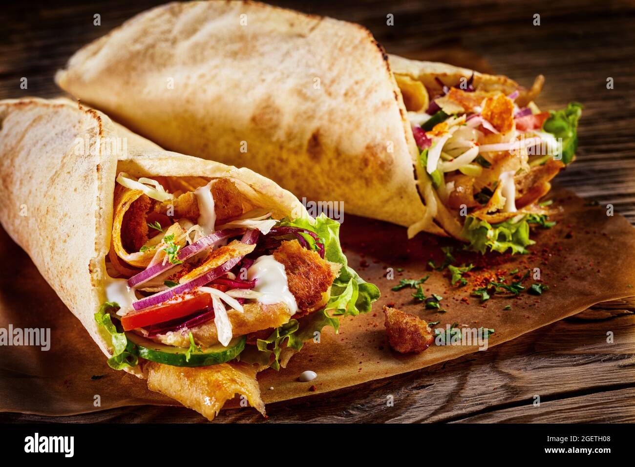 Doner kebab in pita bread with chicken and vegetables placed on a wooden table Stock Photo