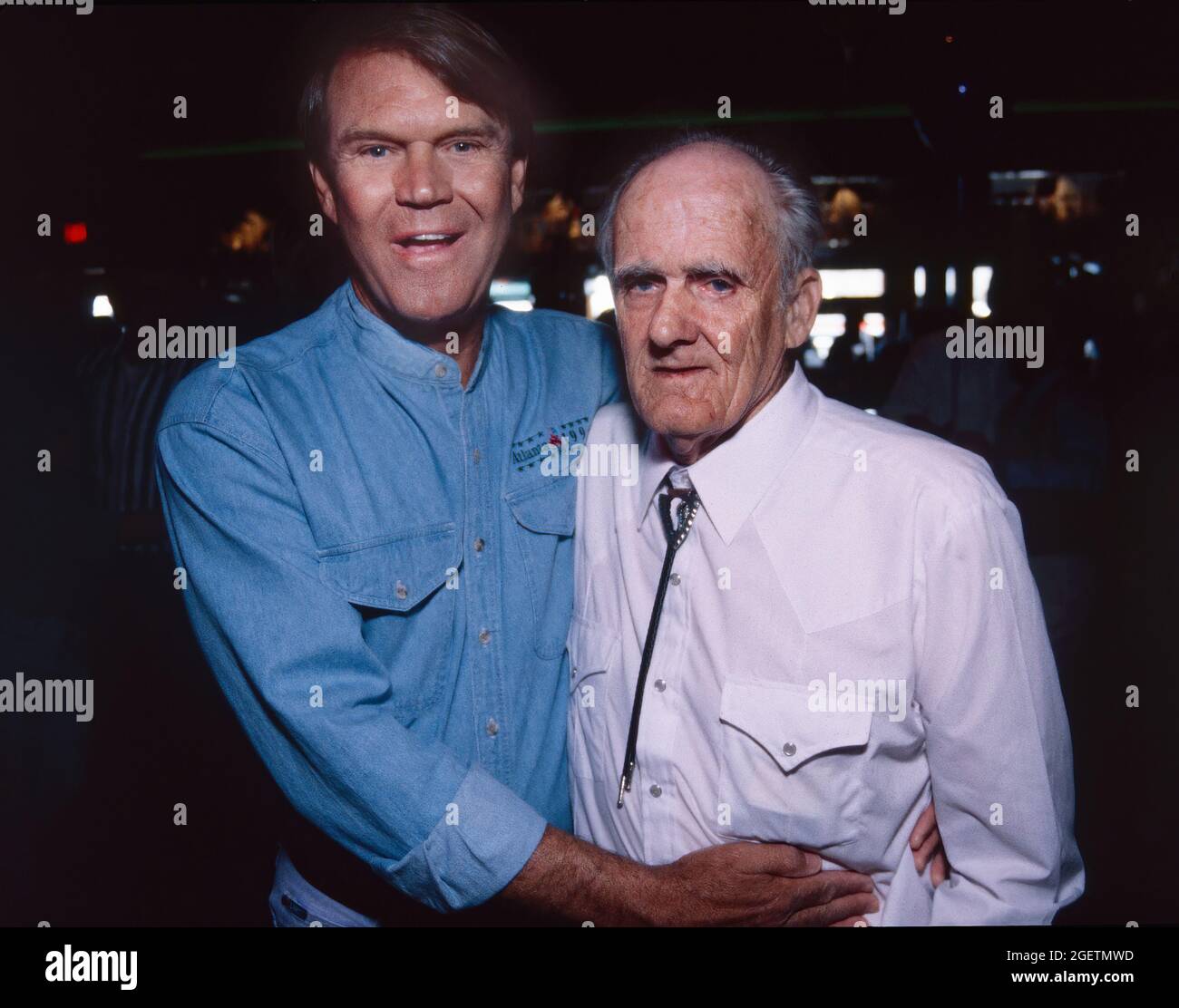 Glen Campbell and his uncle William Eugene 'Boo' Campbell share a moment at Glen Campbell's surprise 60th birthday party in Branson, Missouri on April 21, 1996. Glen Campbell's actual birth date was April 22, 1936. He died of complications from Alzheimer's disease on August 8, 2017. 'Uncle Boo' is credited by Glen Campbell for teaching him to play guitar as a boy. Stock Photo