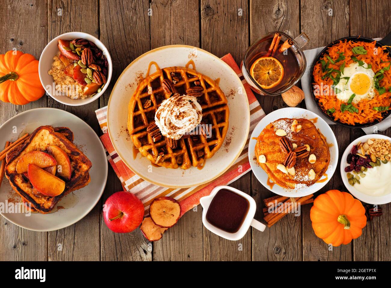 Fall breakfast or brunch buffet table scene against a dark wood background. Pumpkin spice, waffles, pancakes, apple french toast, oatmeal, egg skillet Stock Photo