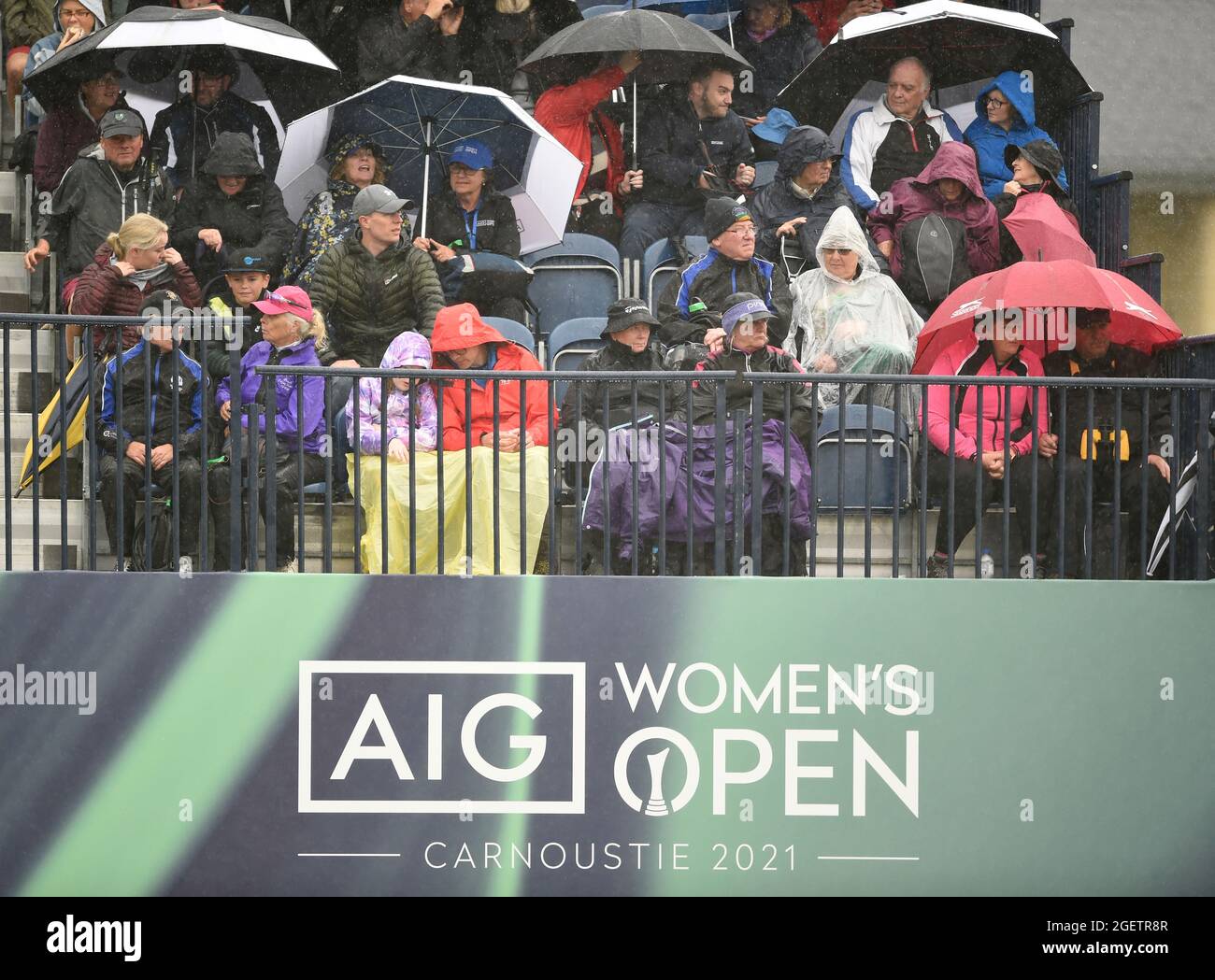 Spectators brave the rain in the stands at the 18th green during day three of the AIG Women's Open at Carnoustie. Picture date: Saturday August 21, 2021. See PA story GOLF Women. Photo credit should read: Ian Rutherford/PA Wire. RESTRICTIONS: Use subject to restrictions. Editorial use only, no commercial use without prior consent from rights holder. Stock Photo