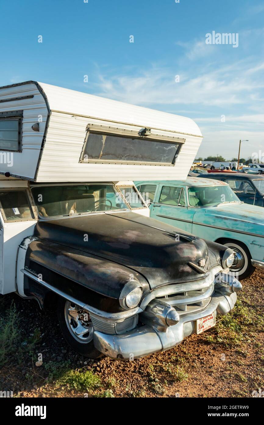 vintage 1955 Cadillac American camper van and cars in a desert junk