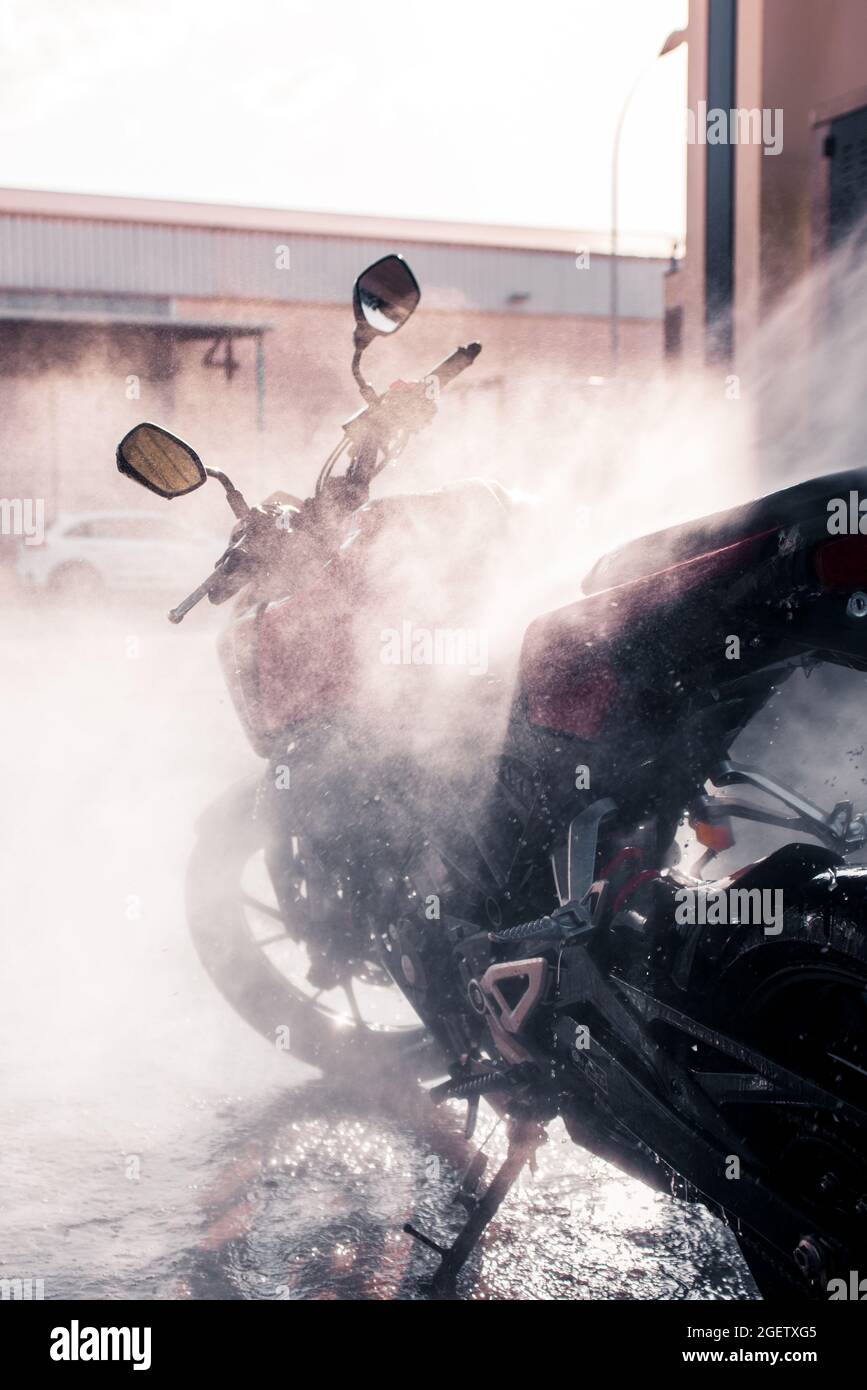 Vertical shot of a modern motorcycle being cleaned with a water spray