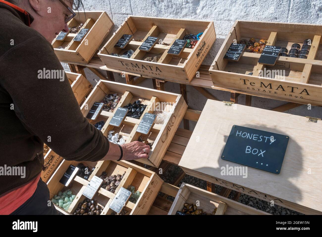 A woman looking at fossils & rock samples for sale, with payment made in an honesty box.  At Uyeasound on Unst, Shetland. Stock Photo