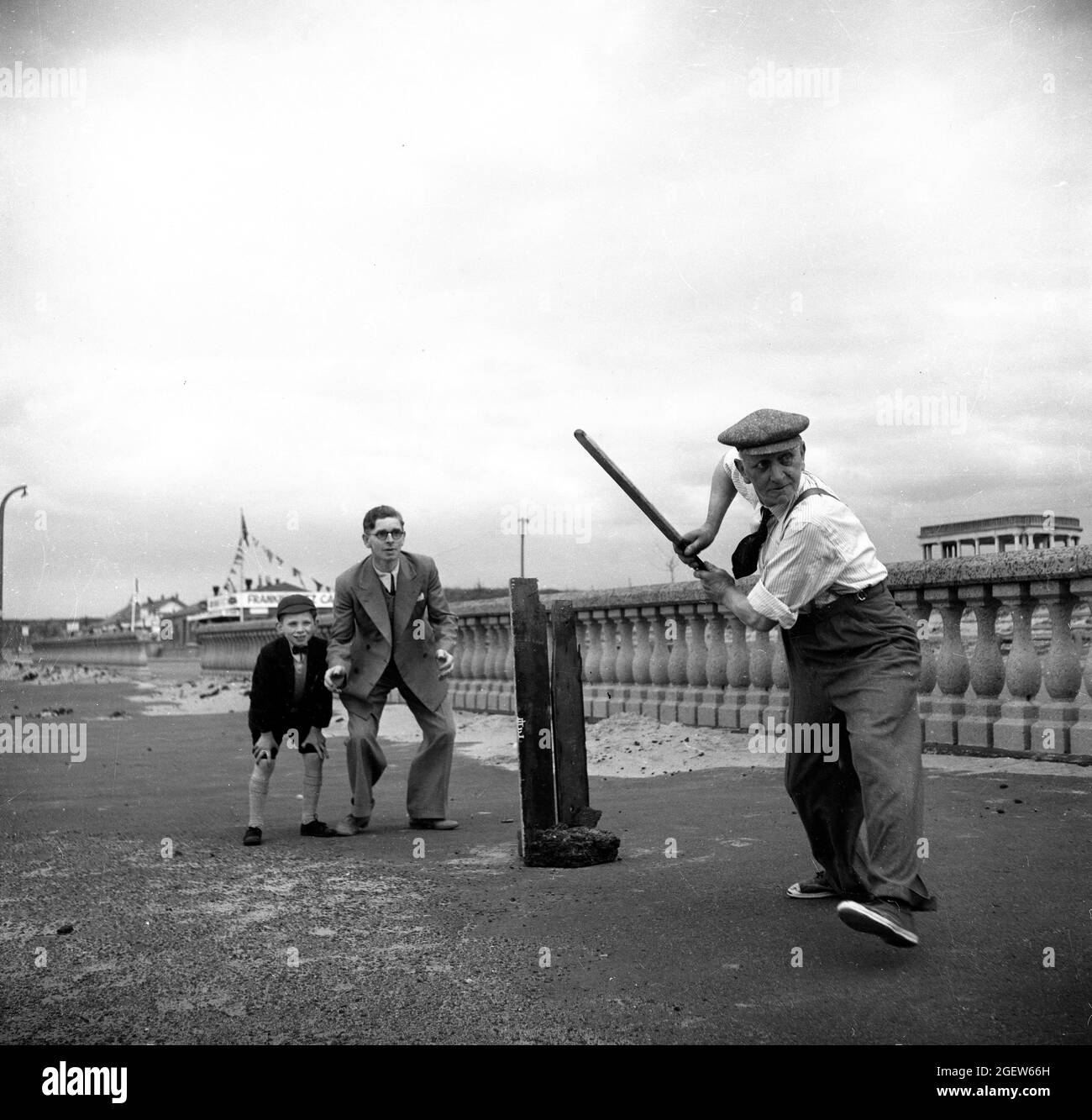 Family playing makeshift cricket at the seaside Britain 1950s Stock Photo