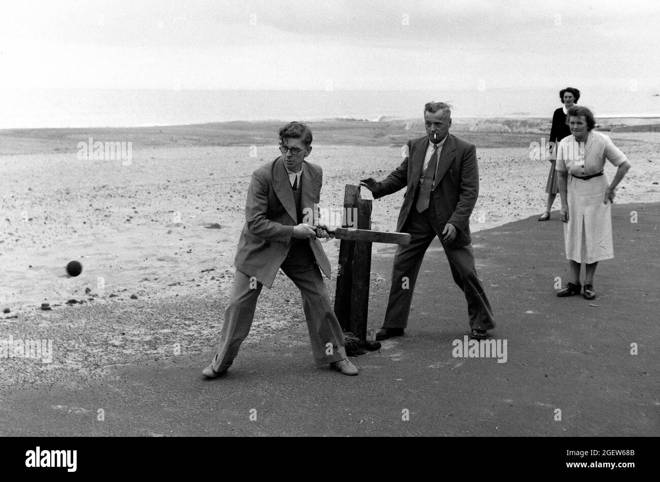 Family playing makeshift cricket at the seaside Britain 1950s Stock Photo