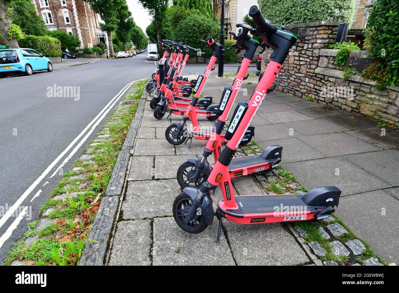 A row of Voi-e-Scooters seen ready for people to hire by mobile phone which is attached to the middle of the handlebar. classed as a road vehicle Stock Photo