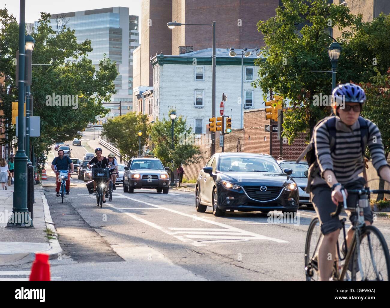 Cyclists commuting on city streets bike lanes with cars and traffic, University City, Philadelphia, Pennsylvania, USA Stock Photo