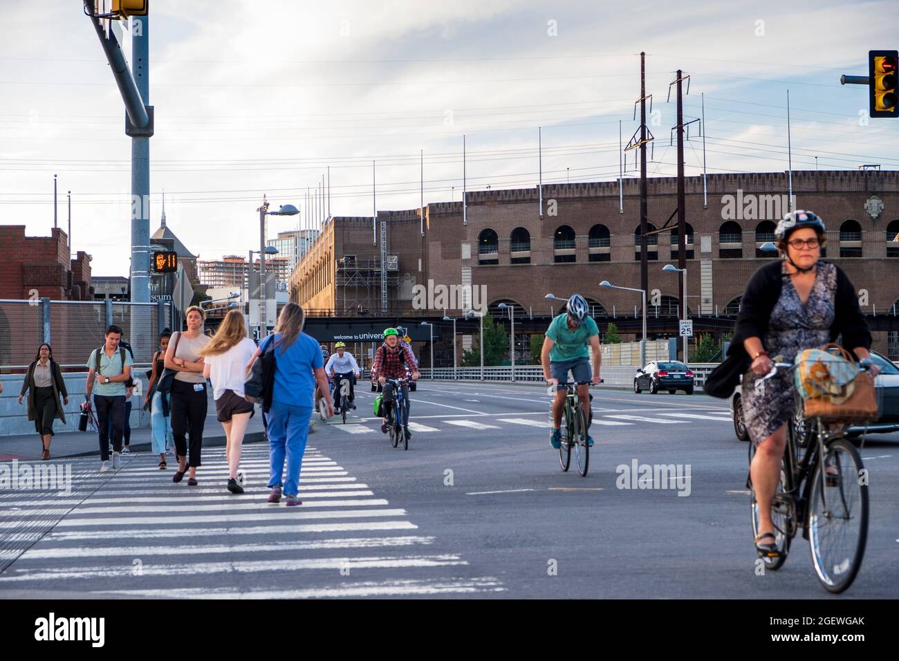 Cyclists commuting on city streets bike lanes with cars and traffic and pedestrians , University City, Philadelphia, Pennsylvania, USA Stock Photo