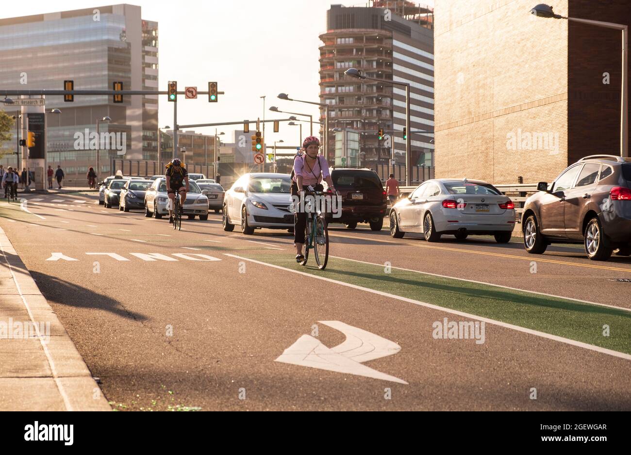 Cyclists commuting on city streets bike lanes with cars and traffic, University City, Philadelphia, Pennsylvania, USA Stock Photo