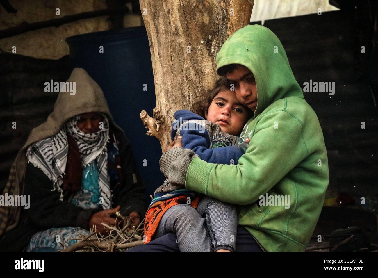 A mother cooking while the older child looks after the younger child ...
