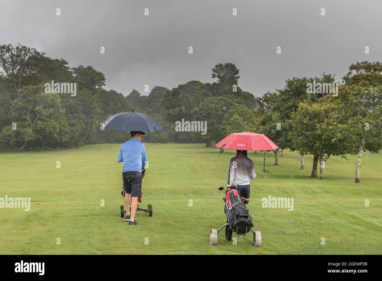 Kenmare, Kerry, Ireland. 21st August, 2021. Father and son, Patrick and Darragh Crushell brave the elements and make their way up the fairway as a torrential downpour falls during their game  of golf at Kenmare, Co. Kerry, Ireland. - Picture; David Creedon- Picture; David Creedon / Alamy Live News Stock Photo