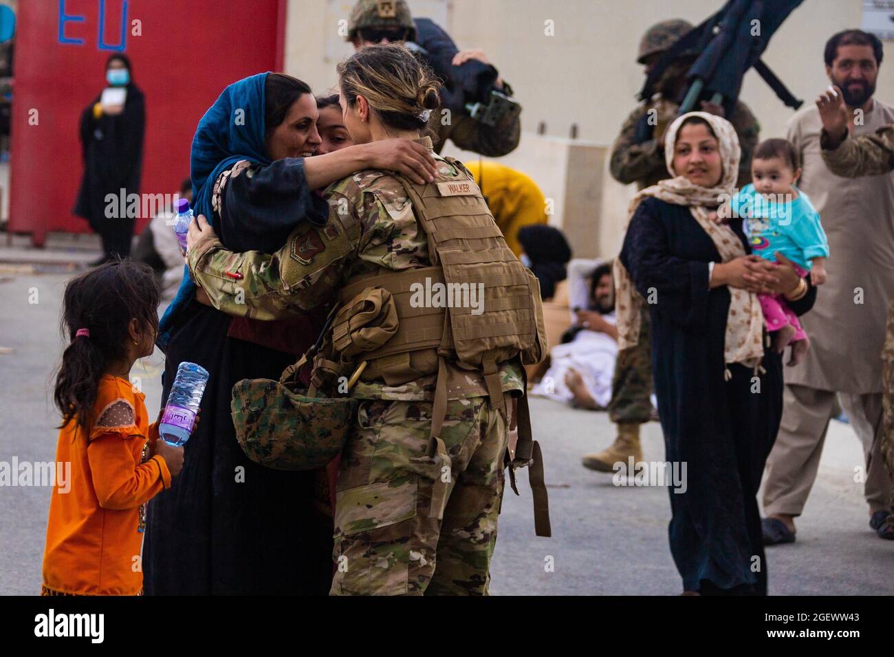 A U.S. Airman with the Joint Task Force-Crisis Response embraces mother after helping reunite their family at Hamid Karzai International Airport, Afghanistan, Aug. 20. U.S. service members are assisting the Department of State with a Non-combatant Evacuation Operation (NEO) in Afghanistan. (U.S. Marine Corps photo by Cpl. Davis Harris) Stock Photo
