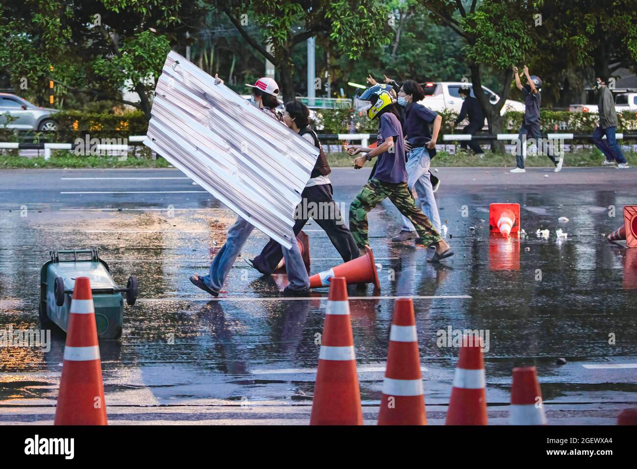 Protesters using a metal sheet to shield against police rubber bullets on Vibhavadi Rangsit road