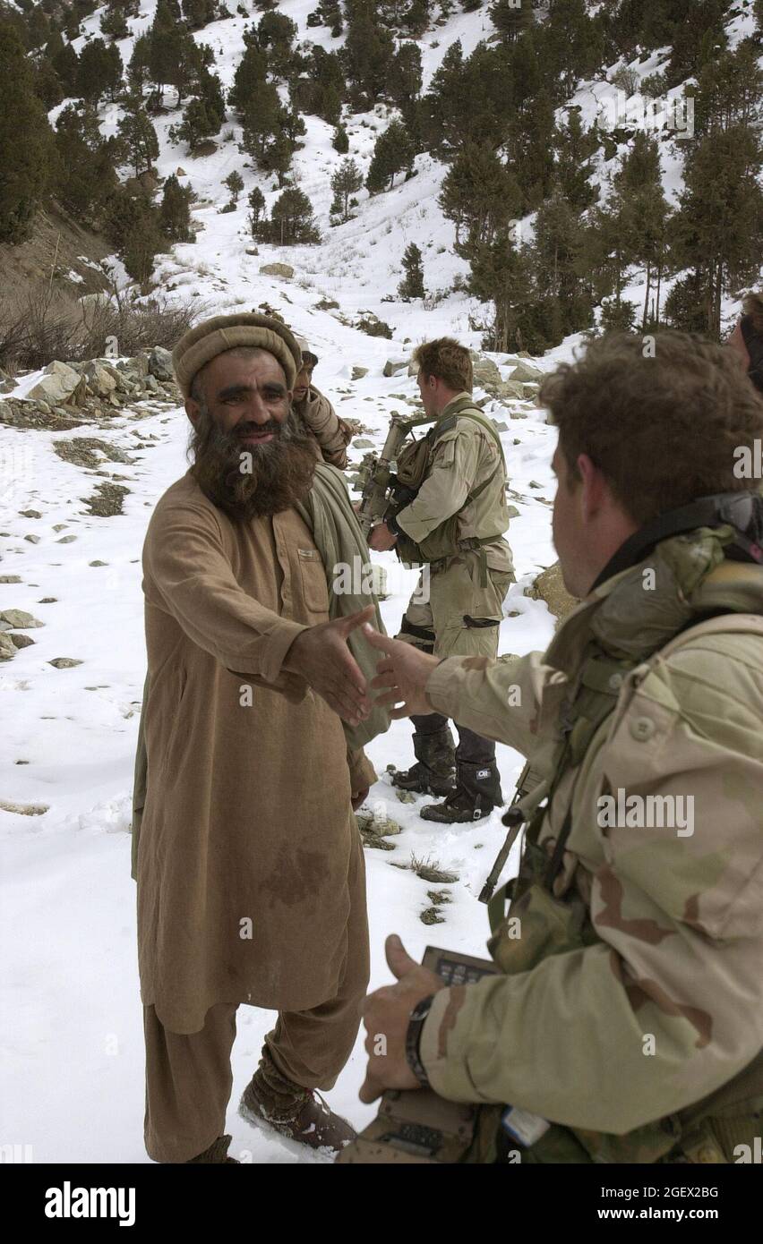 A U.S. Navy SEAL (Sea, Air, Land) talks to local Afghanis while conducting a Sensitive Site Exploitation (SSE) mission in the Jaji mountains, Feb. 12, 2002.  Navy Special Operations Forces are conducting missions in Afghanistan in support Operation Enduring Freedom.  (U.S. Navy photo by Petty Officer 1st Class Tim Turner) Stock Photo
