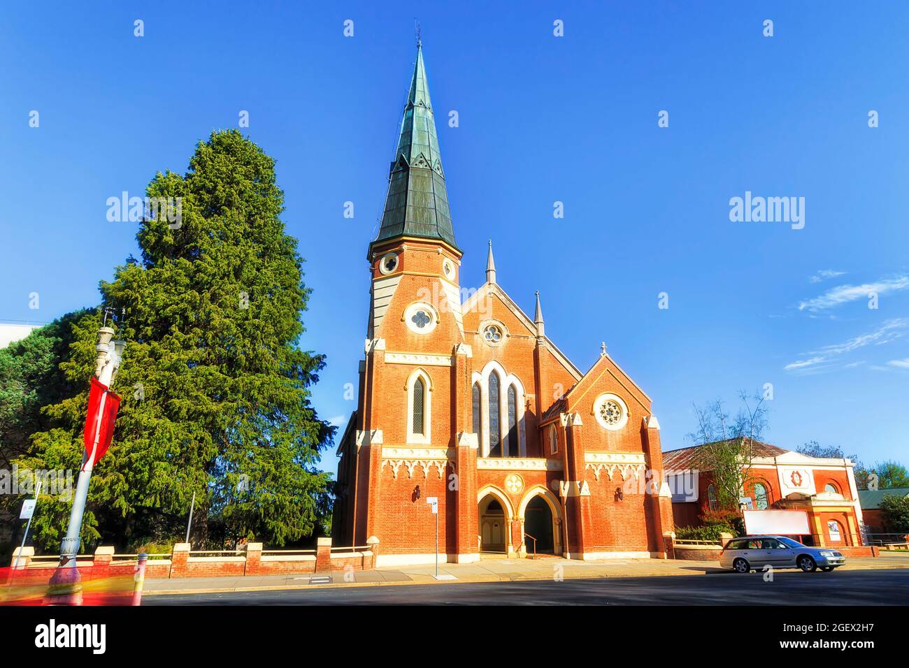Local street in Bathurst town with historic red brick uniting church building under blue sky. Stock Photo