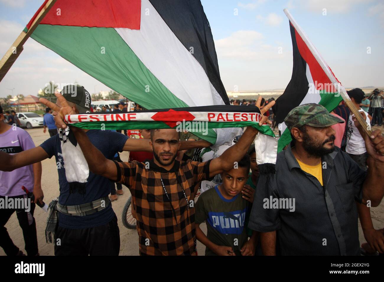 Gaza, Gaza. 21st Aug, 2021. Palestinian protesters lift national flags gesture during a demonstration by the border fence with Israel, east of Gaza City, to denounce the Israeli siege of the Palestinian strip and express support for Jerusalem's Al-Aqsa mosque, Saturday, August 21, 2021. Photo by Ismael Mohamad/UPI Credit: UPI/Alamy Live News Stock Photo