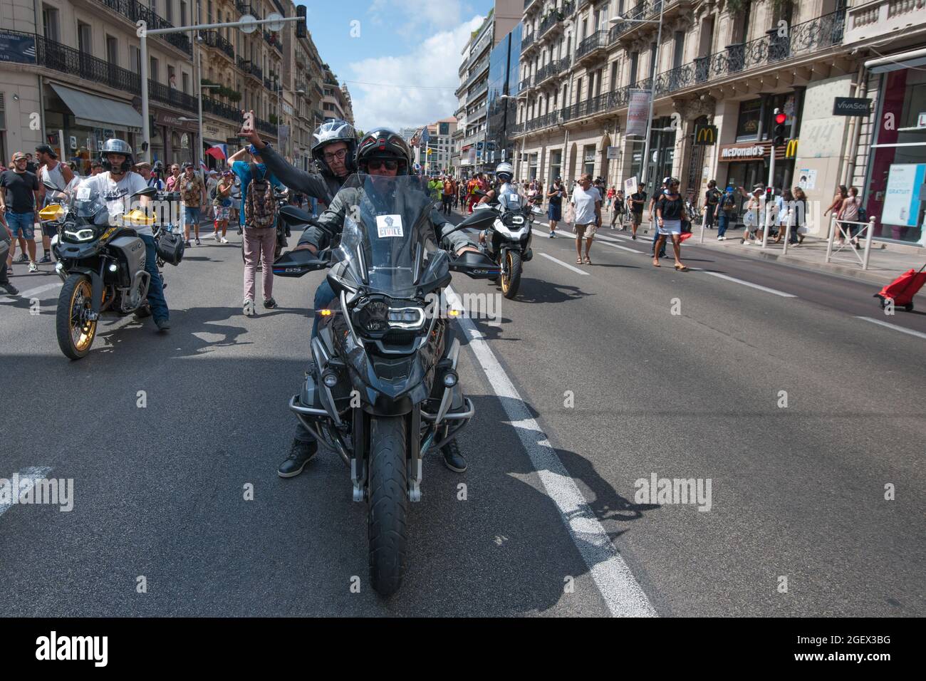 Toulon, France. 21st Aug, 2021. A demonstrator on a motorcycle gesturing the V of victory, during the protest.Saturday 21 August 2021 is the sixth day of mobilization against the vaccine policy and the application of the health pass. In Toulon (Var), according to the authorities there were 6000 demonstrators. The main slogans criticize the government decisions as dictatorial. Some of the placards included signs and slogans comparing the current situation with the Nazi regime and the Second World War. (Photo by Laurent Coust/SOPA Images/Sipa USA) Credit: Sipa USA/Alamy Live News Stock Photo