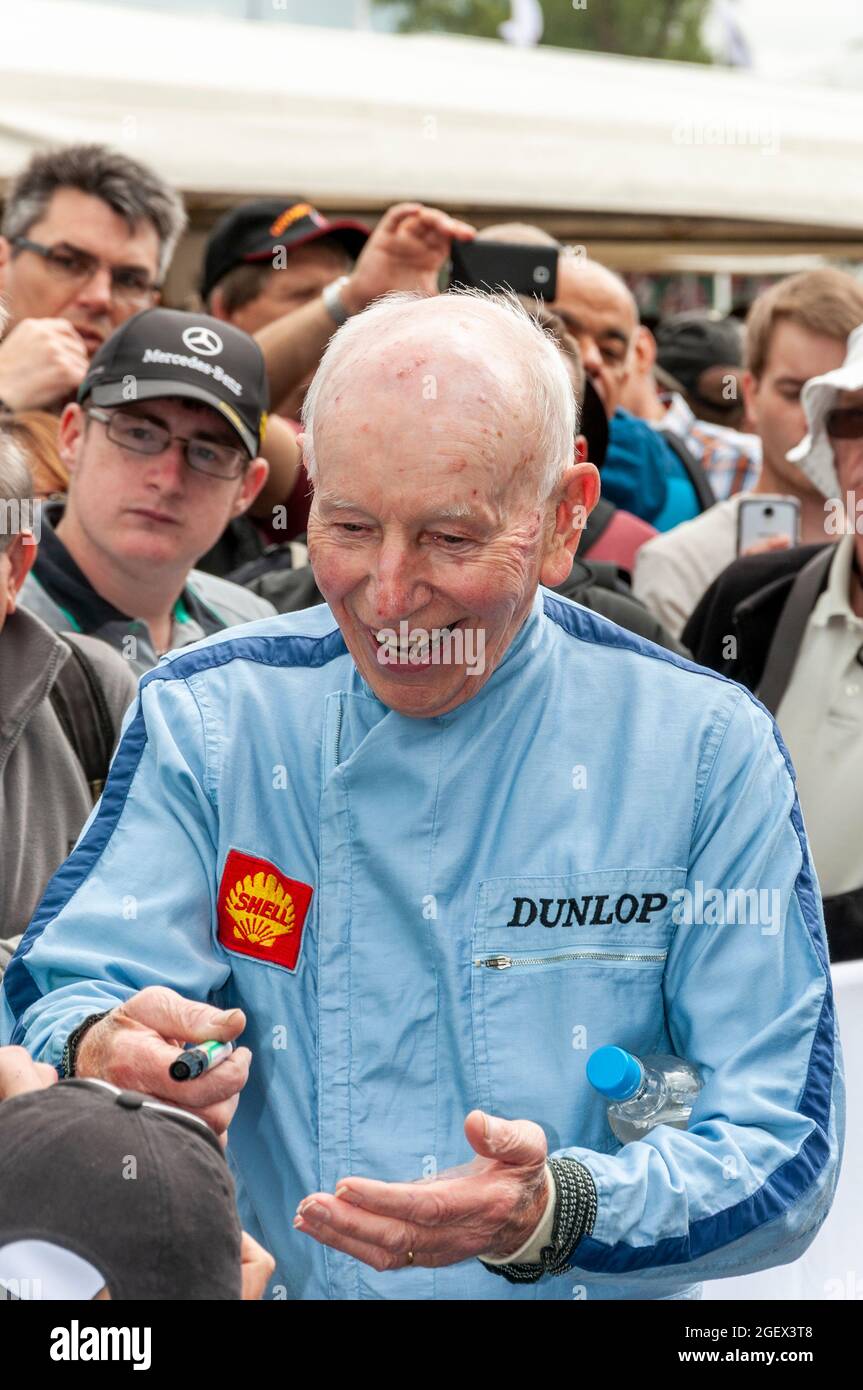 John Surtees signing autographs at the Goodwood Festival of Speed. Legendary Formula 1 Grand Prix racing driver. Joking with a young fan (out of shot) Stock Photo