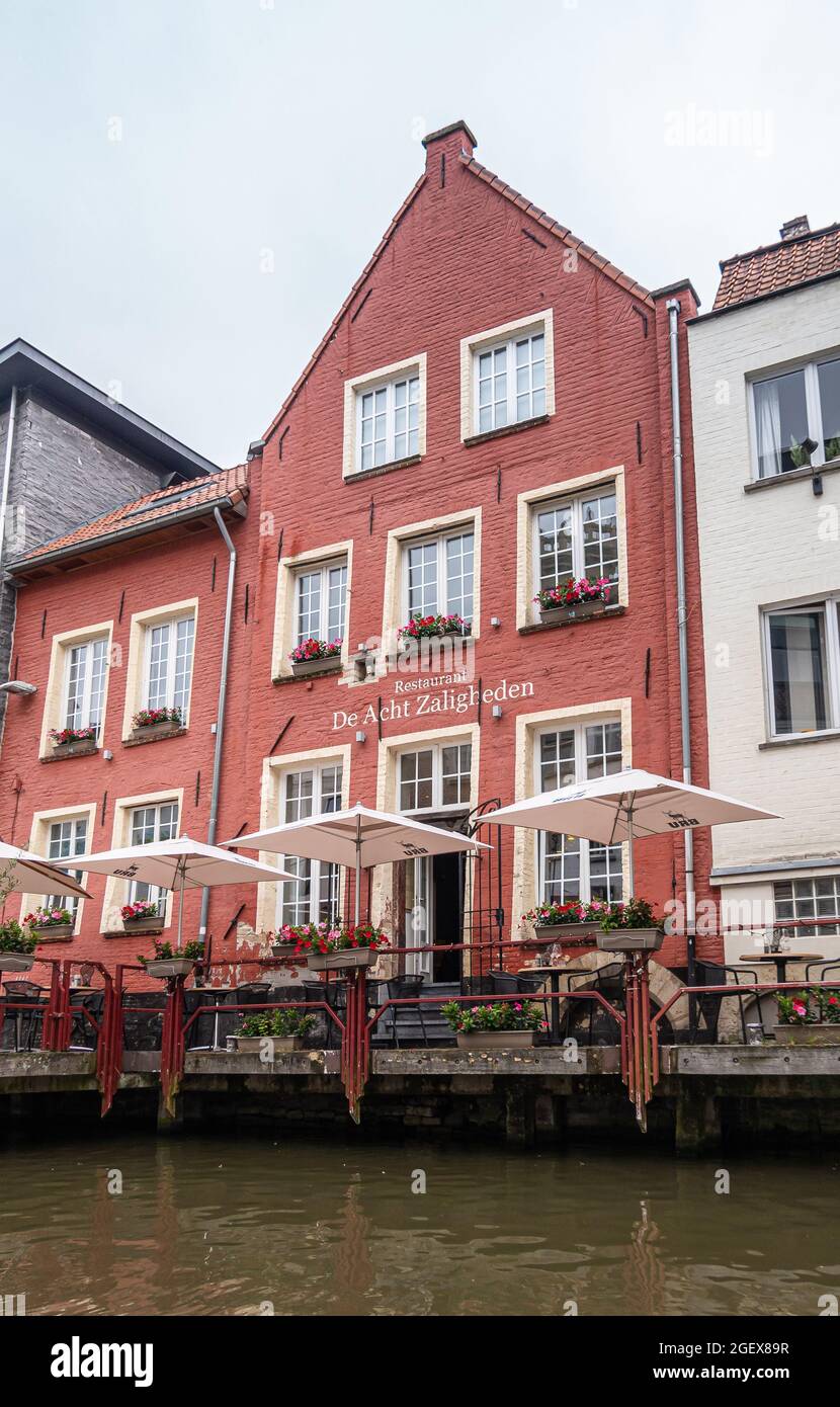 Gent, Flanders, Belgium - July 30, 2021: Leie River side of famous Acht Zaligheden (8 Salvations) restaurant with ox-blood red facade and white umbrel Stock Photo