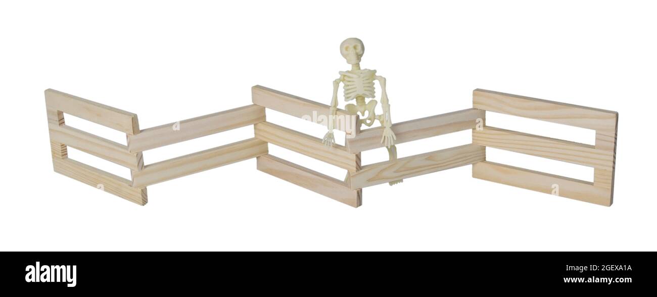 Skeleton standing at a Wooden fence used to contain an area - path included Stock Photo