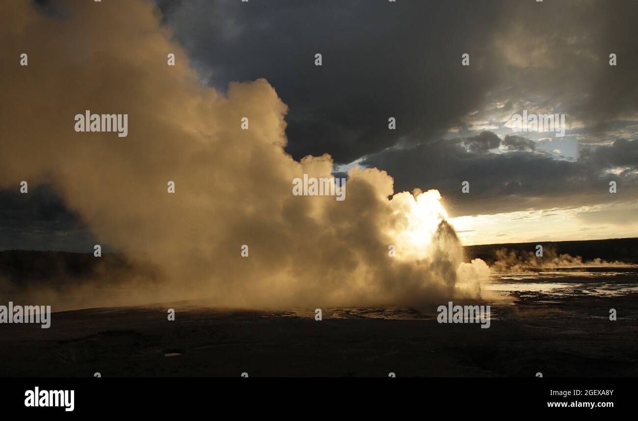 The sun shines behind a geyser eruptionClepsydra Gesyer erupting at sunset ; Date:  16 June 2015 Stock Photo