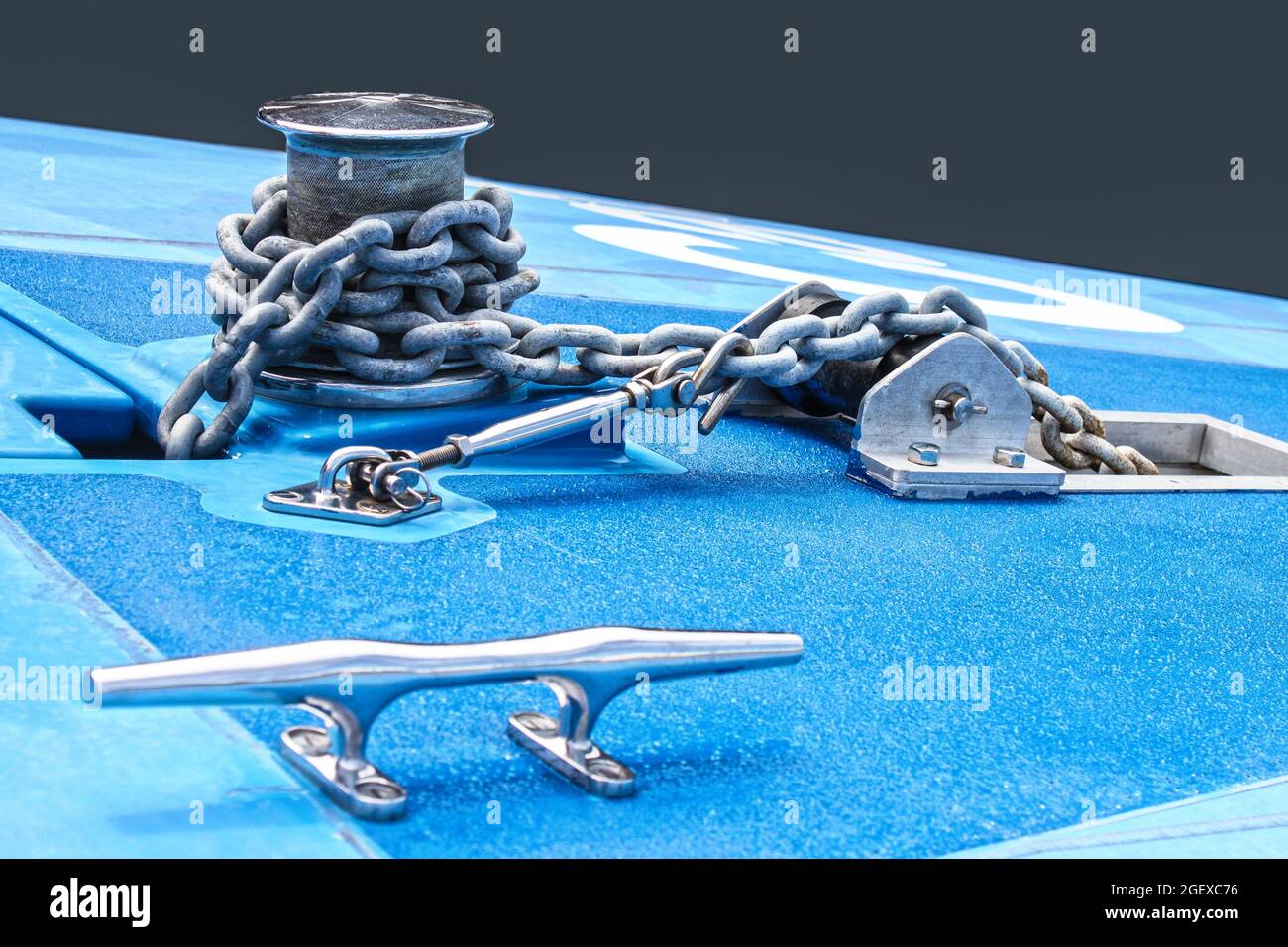 Detail of blue fiberglass boat with chain and grips for handling against gray solid background - selective focus. Stock Photo