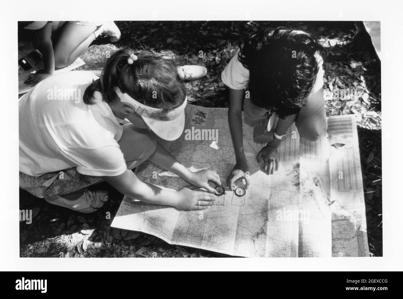 Bandera, Texas USA, circa 1991: Fourth grade girls use compass and map  to estimate their location during an overnight school camping trip. Original in color.  ©Bob Daemmrich Stock Photo
