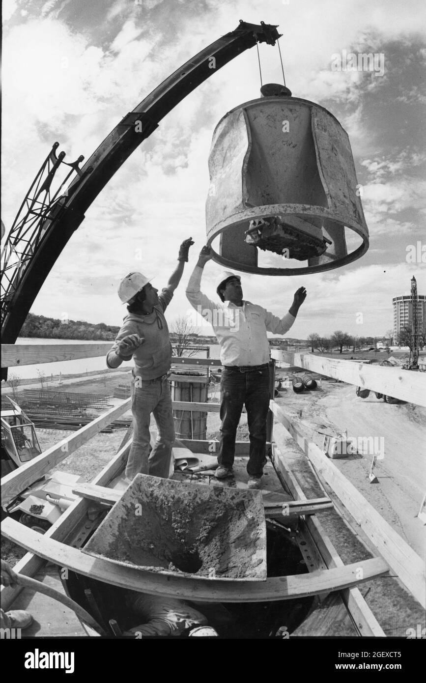 Austin Texas USA, circa 1984: Workers wearing hard hats guide unit into place during bridge construction on Interstate 35 near downtown. ©Bob Daemmrich Stock Photo